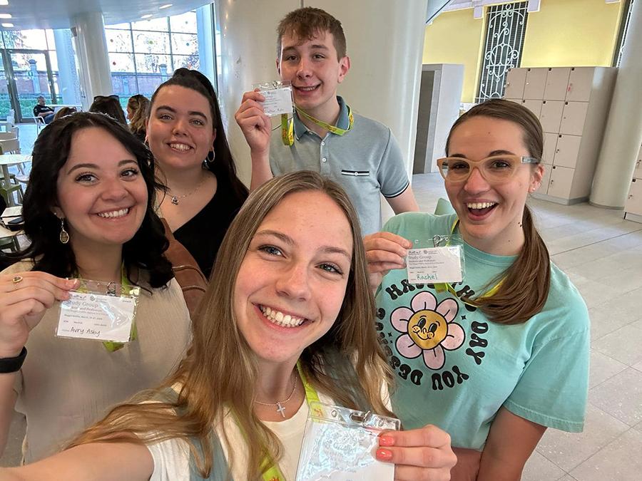 Students Rachel Radcliff, Jonathan Rohr, Jenna Cotter, 阿比·约翰逊和阿夫里·阿斯比在洛里斯·马拉古齐中心报到后展示了他们的官方徽章，这是他们学习雷焦·艾米利亚哲学的第一天.